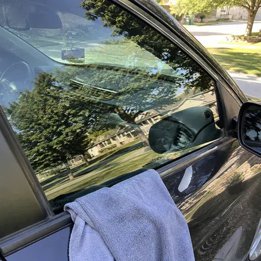 Car side window being cleaned with microfiber towel