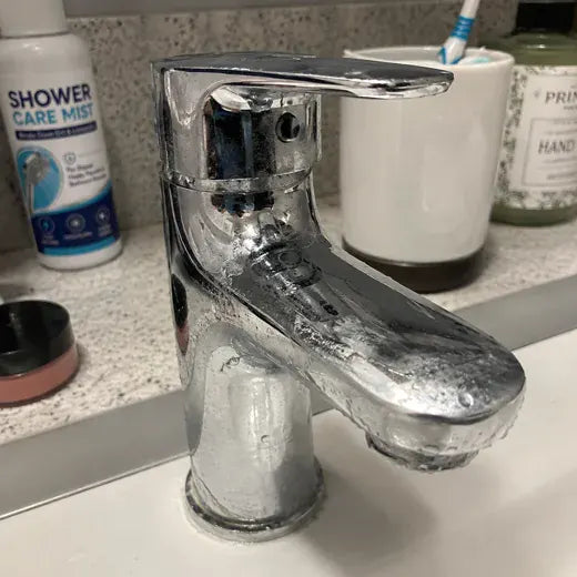 Faucet with cleaner bottle nearby before wiping
